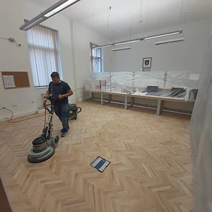 Majstor stručno brusi parket pomoću profesionalne mašine